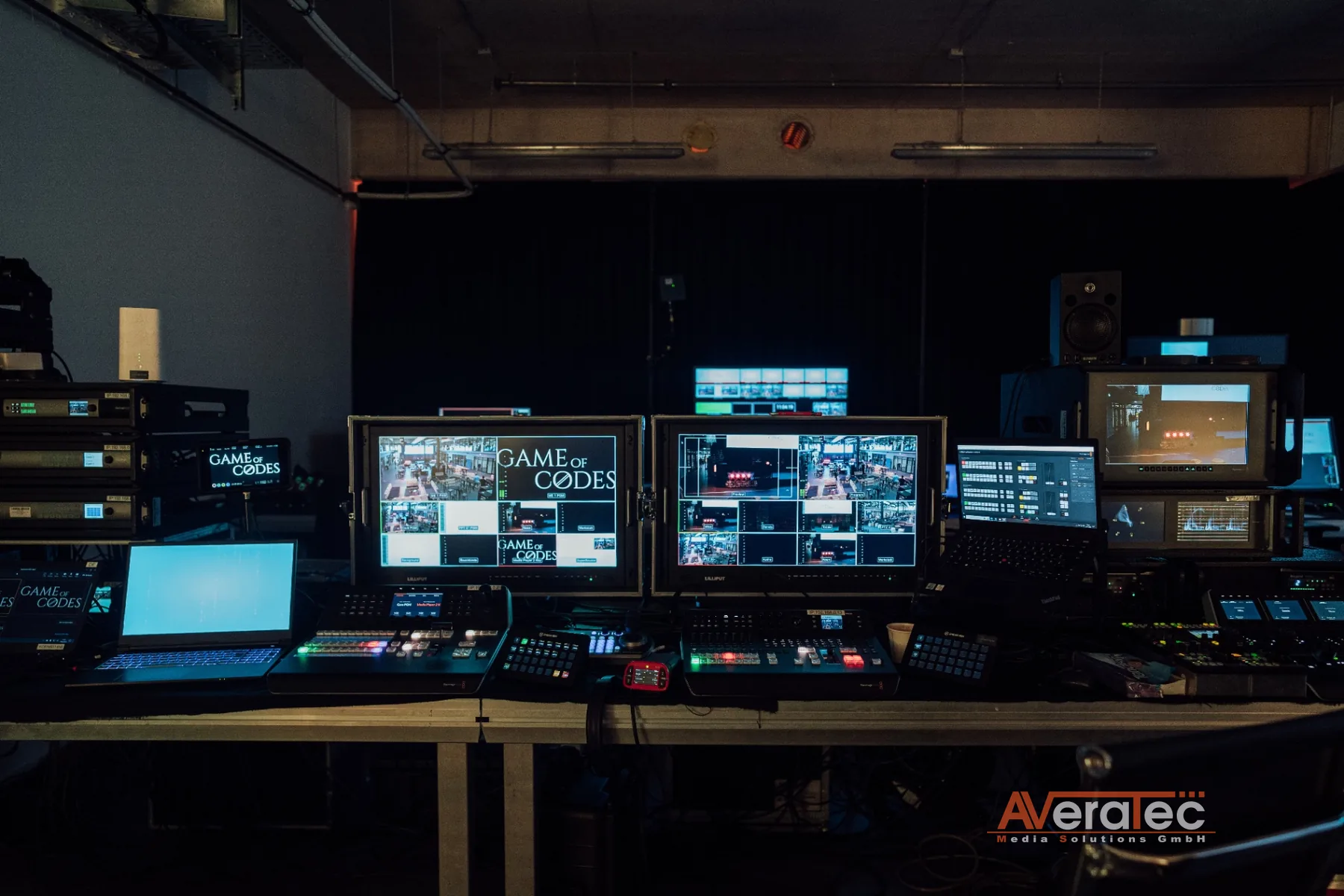 Regie-Arbeitsplatz mit Game-of-Codes-Branding auf den Monitoren