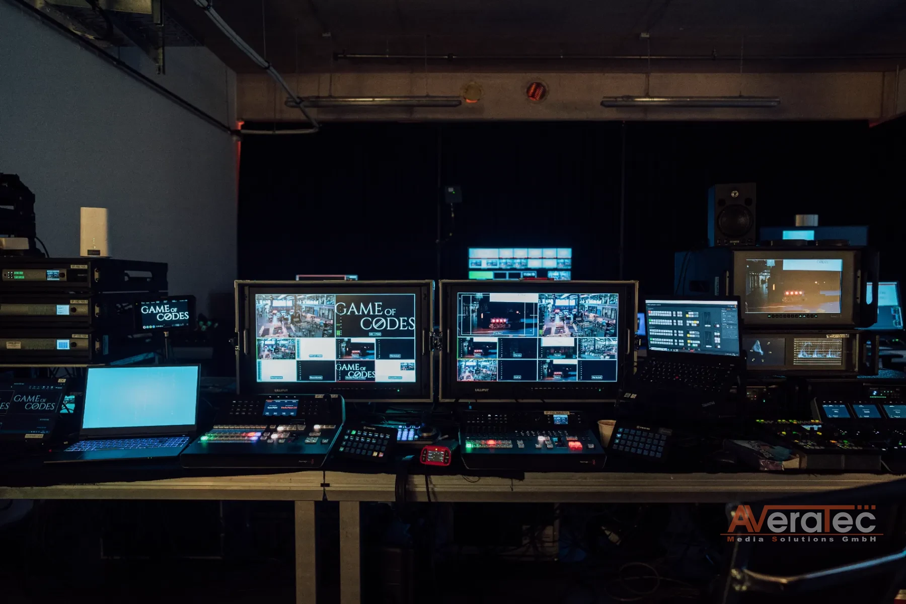 Regie-Arbeitsplatz mit Game-of-Codes-Branding auf den Monitoren